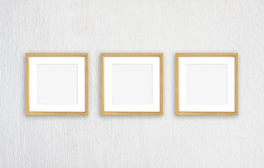 Three blank photo frames isolated on white plastered wall, realistic golden framework mock up