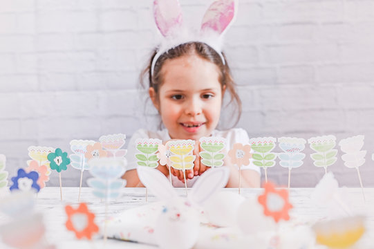 Little girl with bunny ears and easter decoration and eggs on a white background. Cheerful baby on holiday. Free space for text. Copy space.