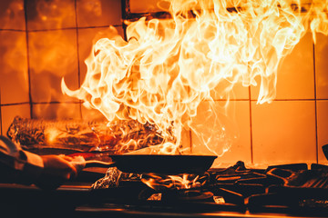 The chef cooking and makes a fire in a pan. Cooking with fire. Crown food. Charismatic chef in the...