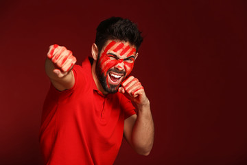 Portrait of aggressive man with paint on his face and hands against color background