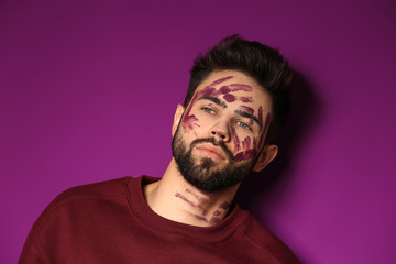 Portrait of handsome man with paint on his face against color background