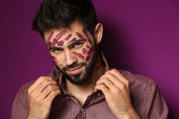 Portrait of handsome man with paint on his face against color background