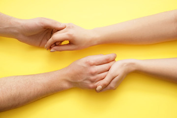 Man and woman holding hands on color background