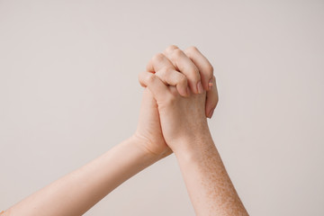 Young women holding hands against light background