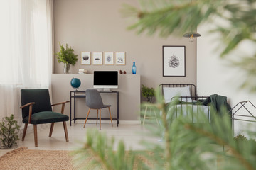 Forest inspiration in teenager's bedroom and workspace interior with retro armchair and natural carpet