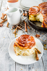 Homemade baking, Cinnamon rolls with sugar frosting. With cinnamon sticks and spices, wooden background copy space
