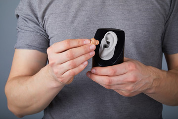 Man showing the use of hearing aid, closeup. The choice of hearing aid hearing care professional 
