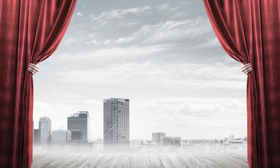 Business city in gray fog behind red curtain and hand holding it
