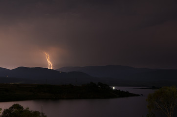 Naklejka na ściany i meble Lightning striking the mountains over a lake
