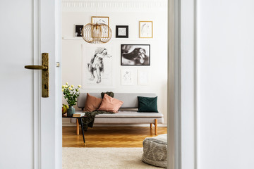Gallery of poster on white wall of stylish living room interior with grey couch and pillows