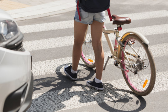 Teenager Walking With Bicycle On The Pedestrian Crossing Next To A Car