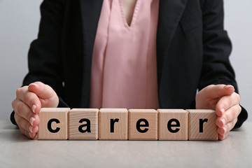 Obraz premium Woman with word CAREER made of cubes at table