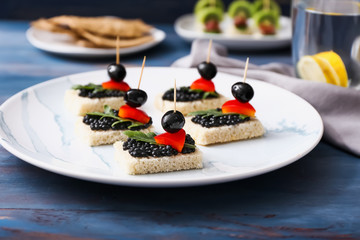 Plate with tasty canapes on wooden table