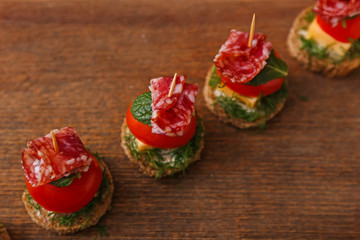 Tasty canapes on wooden background