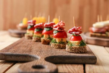 Tasty canapes on wooden board, closeup