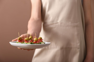 Obraz na płótnie Canvas Woman holding plate with tasty canapes, closeup