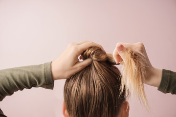 Naklejka premium Young woman doing hair on color background