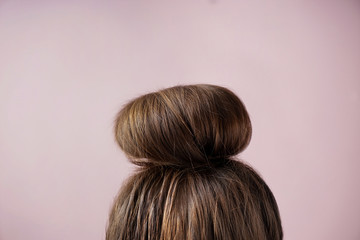 Young woman with hair bun on color background