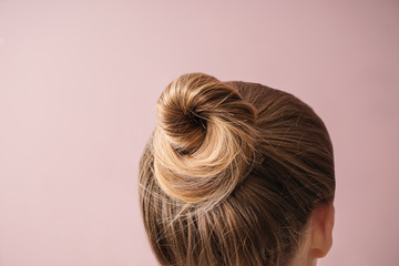 Young woman with hair bun on color background