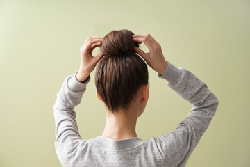 Young woman with hair bun on color background