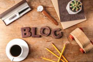 Word BLOG with cup of coffee and stationery on wooden table