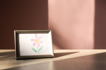 Frame with picture of beautiful flower on table