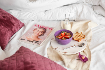 Fototapeta na wymiar Tray with healthy breakfast and magazine on bed