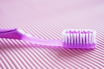 Yellow and purple toothbrush on pink background.