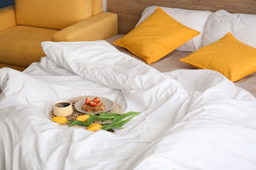 Tasty healthy breakfast and flowers on bed