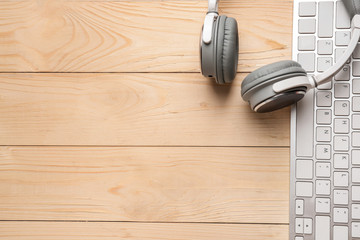 Modern PC keyboard and headphones on wooden table