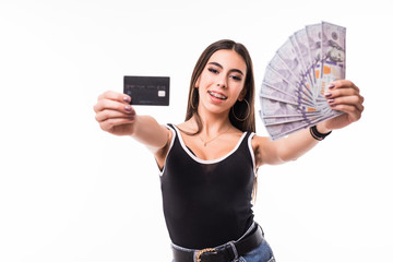 Portrait of brunette woman smiling while holding credit card and fan of dollar cash isolated over white background