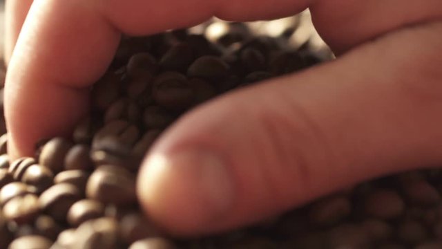 Coffee beans close up. Male hands hold coffee.