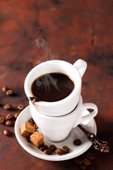 Coffee cup with coffee beans and brown sugar on brown stone background. Copyspace for your text