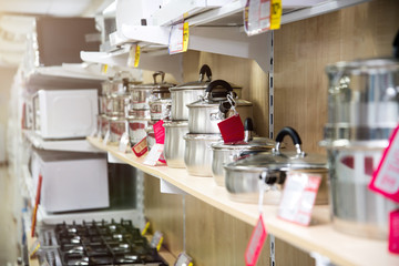 A set of stainless steel utensils on the shelves of the store, close-up. Warm light. Backlight on the left