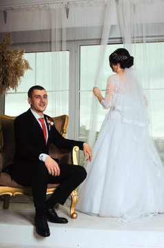 wedding photoshoot in the Studio. the bride and groom posing. groom with a red tie and black business suit. the bride in a white lush dress