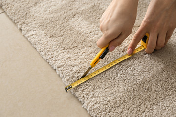 Woman with tape measure cutting carpet
