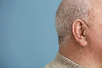 Senior man with hearing problem on color background, closeup - obrazy, fototapety, plakaty