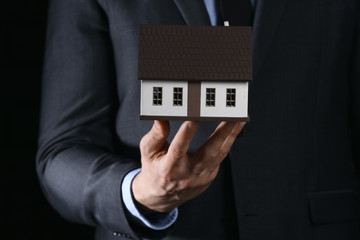 Insurance agent with model of house, closeup. Protection of house from earthquake