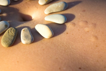 Pattern of small sea stones on women's skin, pebble beach