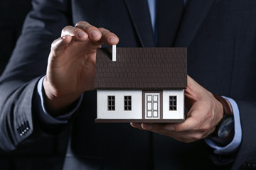 Insurance agent with model of house, closeup. Protection of house from earthquake