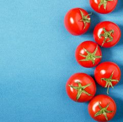 Bright organic tomatoes on a blue background, copy space. - Image