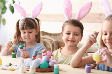 Cute children painting Easter eggs at home