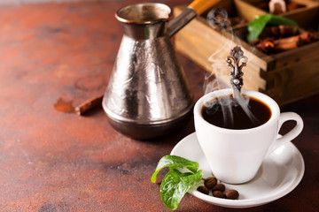 tasting cup of coffee , copper Turk and a wooden box with spice and different coffee roasted beans on stone background,