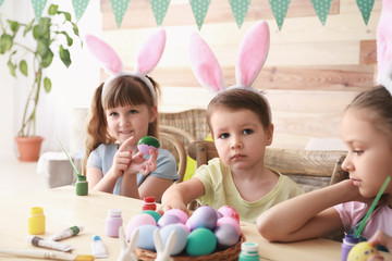 Obraz na płótnie Canvas Cute children painting Easter eggs at home