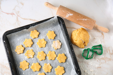 Baking sheet with raw cookies and rolling pin on light table