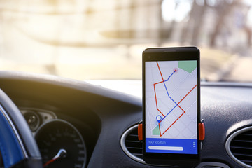 Mobile phone displaying map with route on screen for car driver