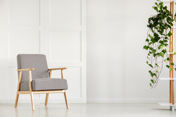 Vintage armchair next to an empty wall in a daily room interior. Real photo. Place your poster