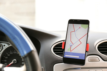 Mobile phone displaying map with route on screen for car driver