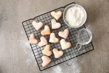 Cooling rack with tasty cookies and sugar powder on grey table