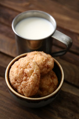 Bowl with tasty cookies and cup of milk on wooden table